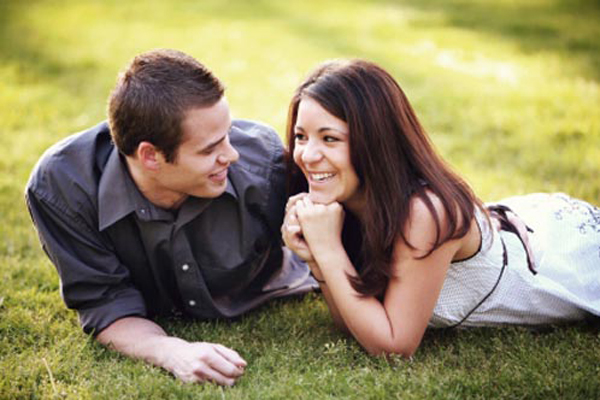 A couple sits on grass being in love