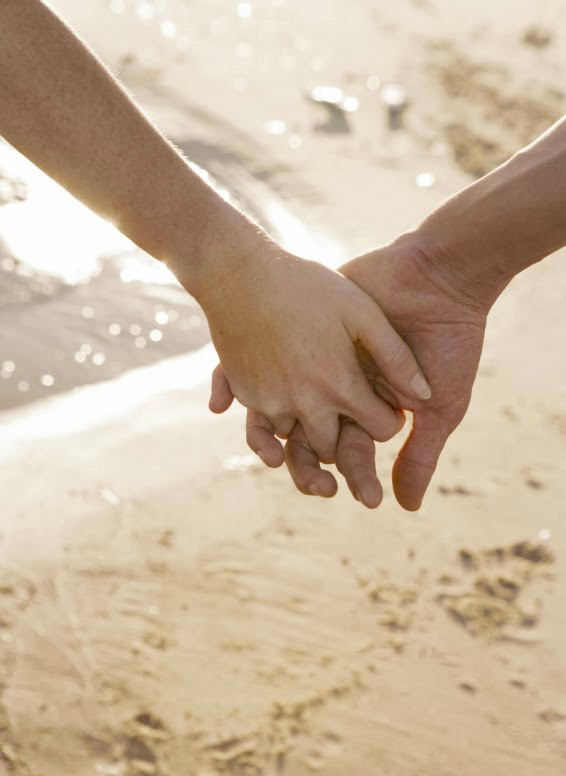 A couples holds hands on the beach finding love where they least expected it