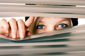 Woman looks through blinds